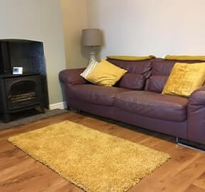 leather sofa, yellow rug and wood burner